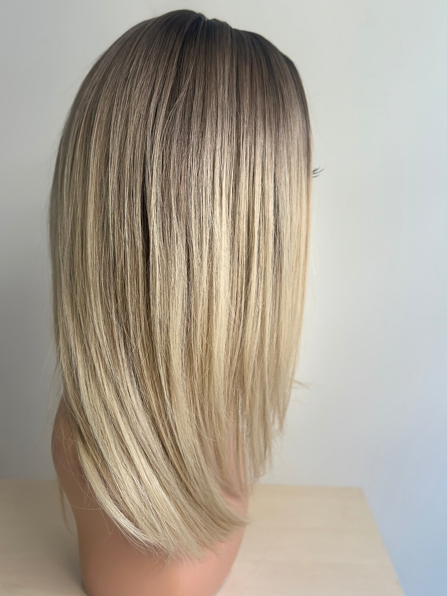 Blonde wig on a mannequin head against a plain background